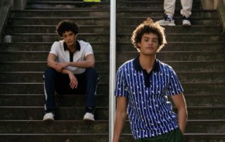 homme qui pose avec un polo lacoste sur assis et debout sur des escaliers